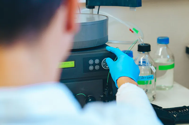 Technicien de laboratoire manipulant un équipement d’analyse en environnement contrôlé, illustrant l’expertise technique de BPM Techcare en Suisse